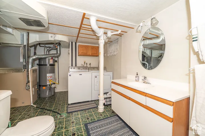 Functional utility space featuring a vanity with integrated sink, a toilet, and laundry hookups