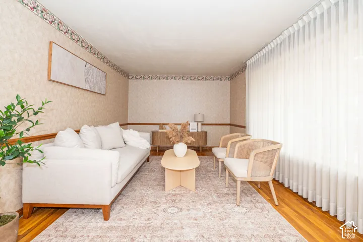 Living area featuring hardwood flooring, patterned wallpaper with decorative borders, and full-wall window treatments