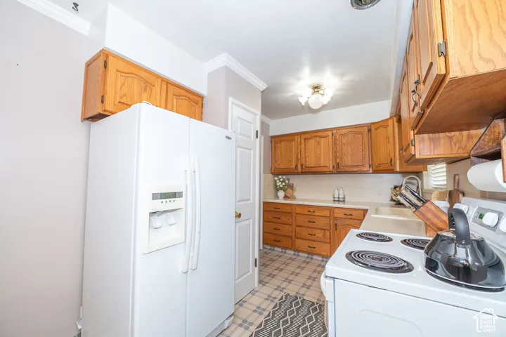 Kitchen featuring wood cabinetry, light-toned countertops, and a white side-by-side refrigerator
