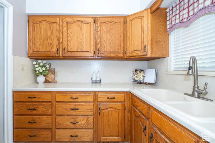 Kitchen with wood cabinetry, a built-in sink, solid surface countertops, and a full backsplash