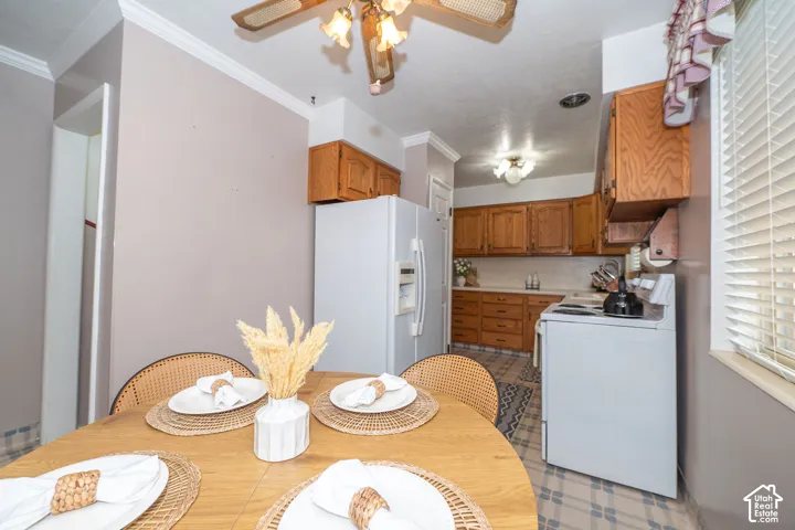 Dining area featuring a wood-finish table, crown molding, and a ceiling fan with light fixture