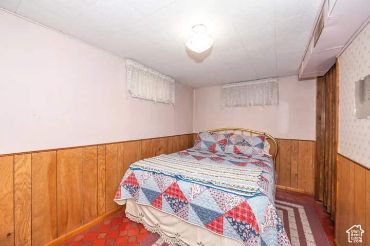 Room featuring light pink walls, wood paneling, and a white acoustical tile ceiling