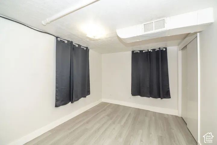 Interior room featuring wood-finish flooring, white walls, and a built-in closet with white bifold doors