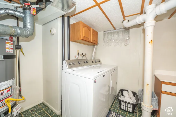 Dedicated laundry area featuring a washer and dryer, adjacent to a water heater