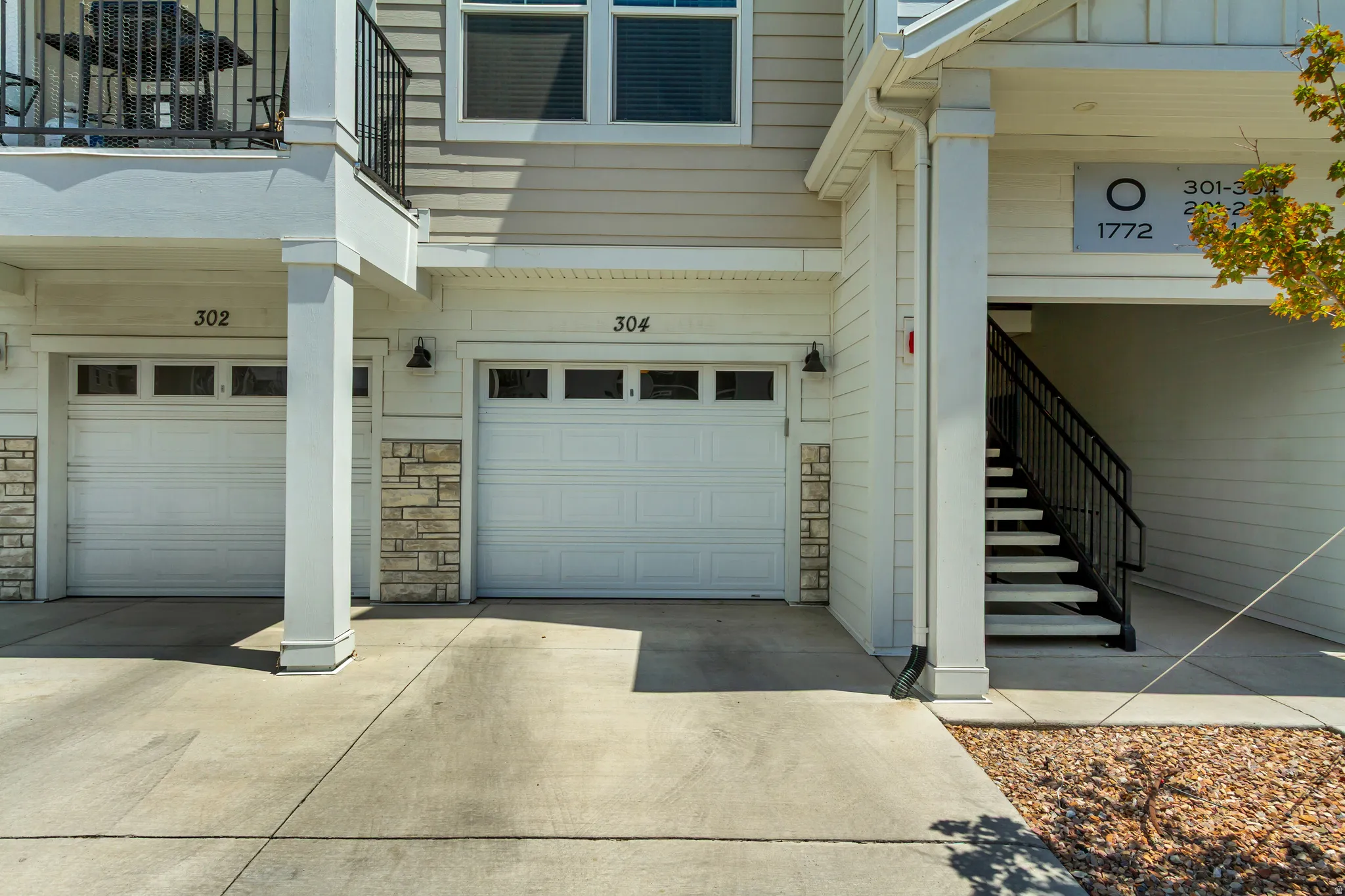 Facade featuring two single-car garages, an external staircase, and a second-story balcony
