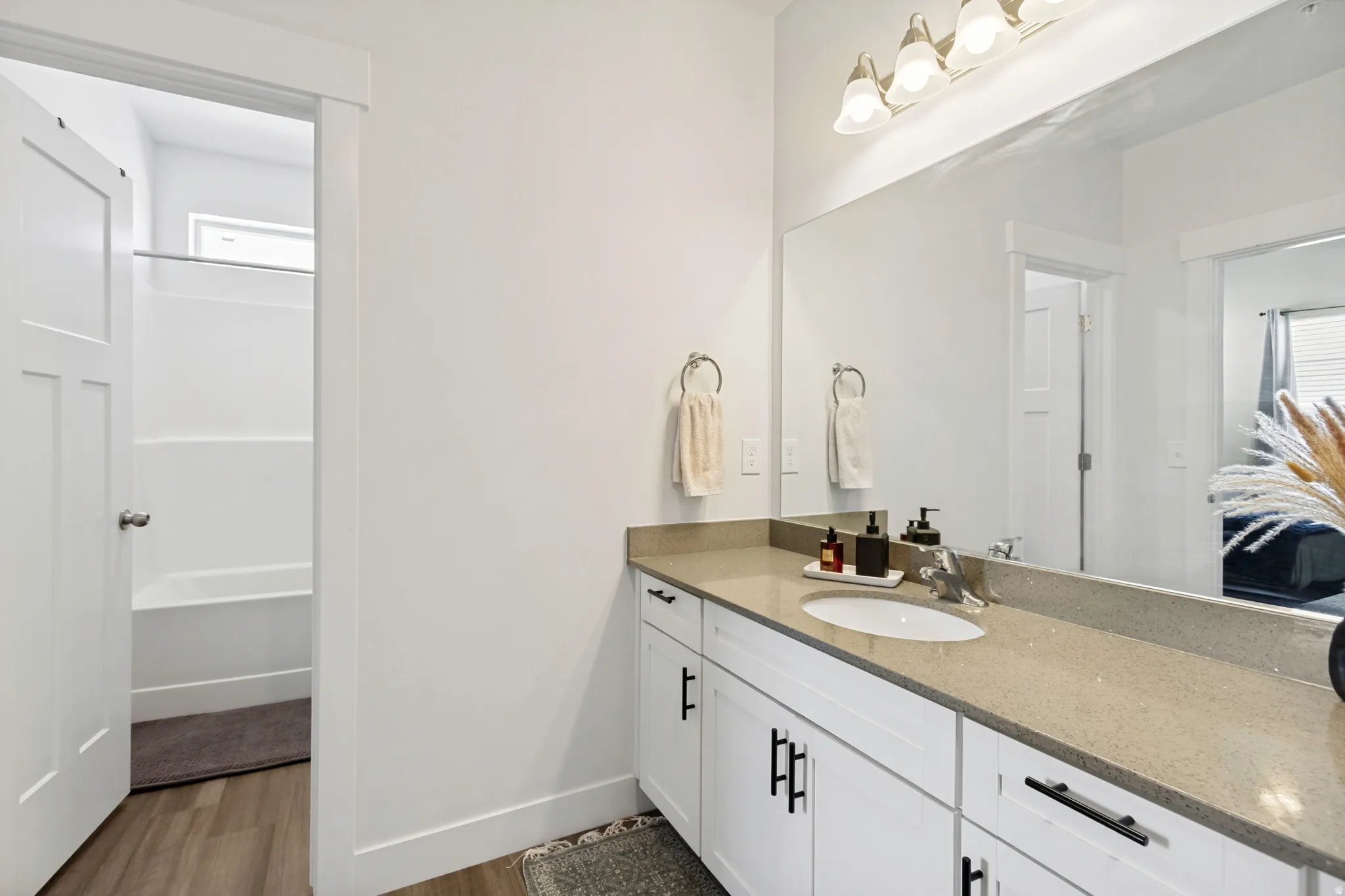 Bathroom featuring a spacious vanity with a light-toned countertop, an integrated sink, and white cabinetry