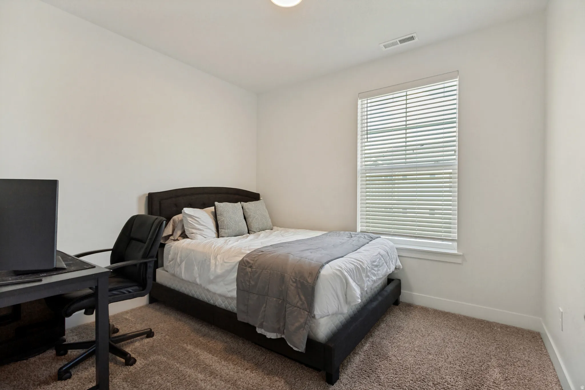 Bedroom featuring neutral wall tones and a single window with horizontal blinds