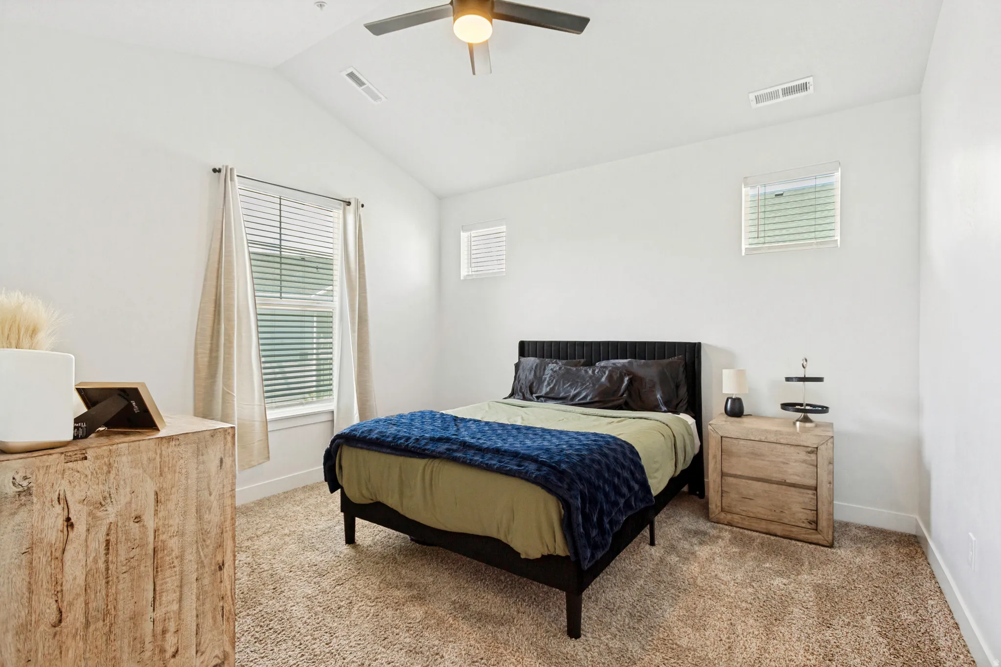 Carpeted room featuring a vaulted ceiling with a flush-mount ceiling fan