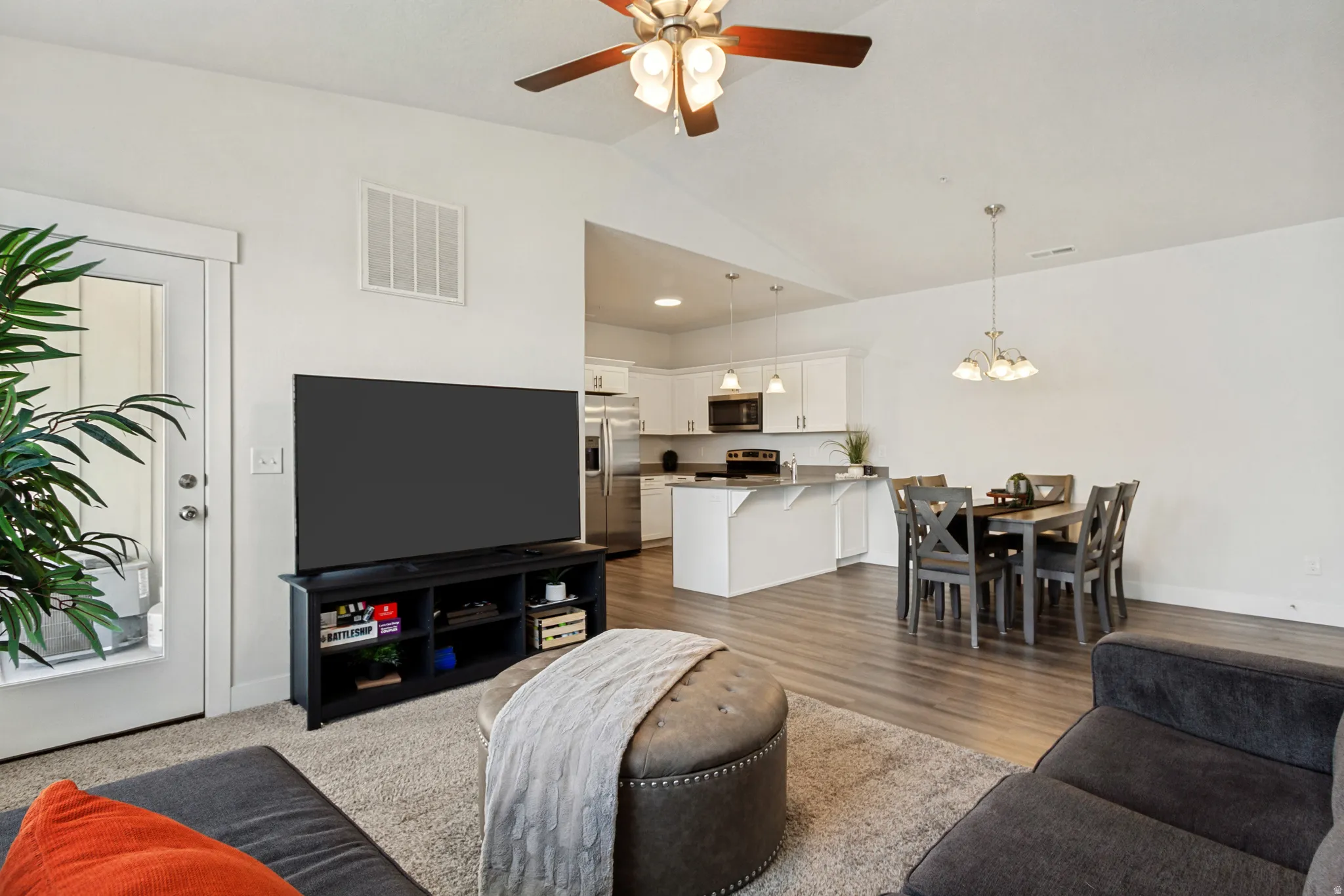 Open-concept living space featuring vaulted ceilings, wood-finish flooring, a ceiling fan, and recessed lighting
