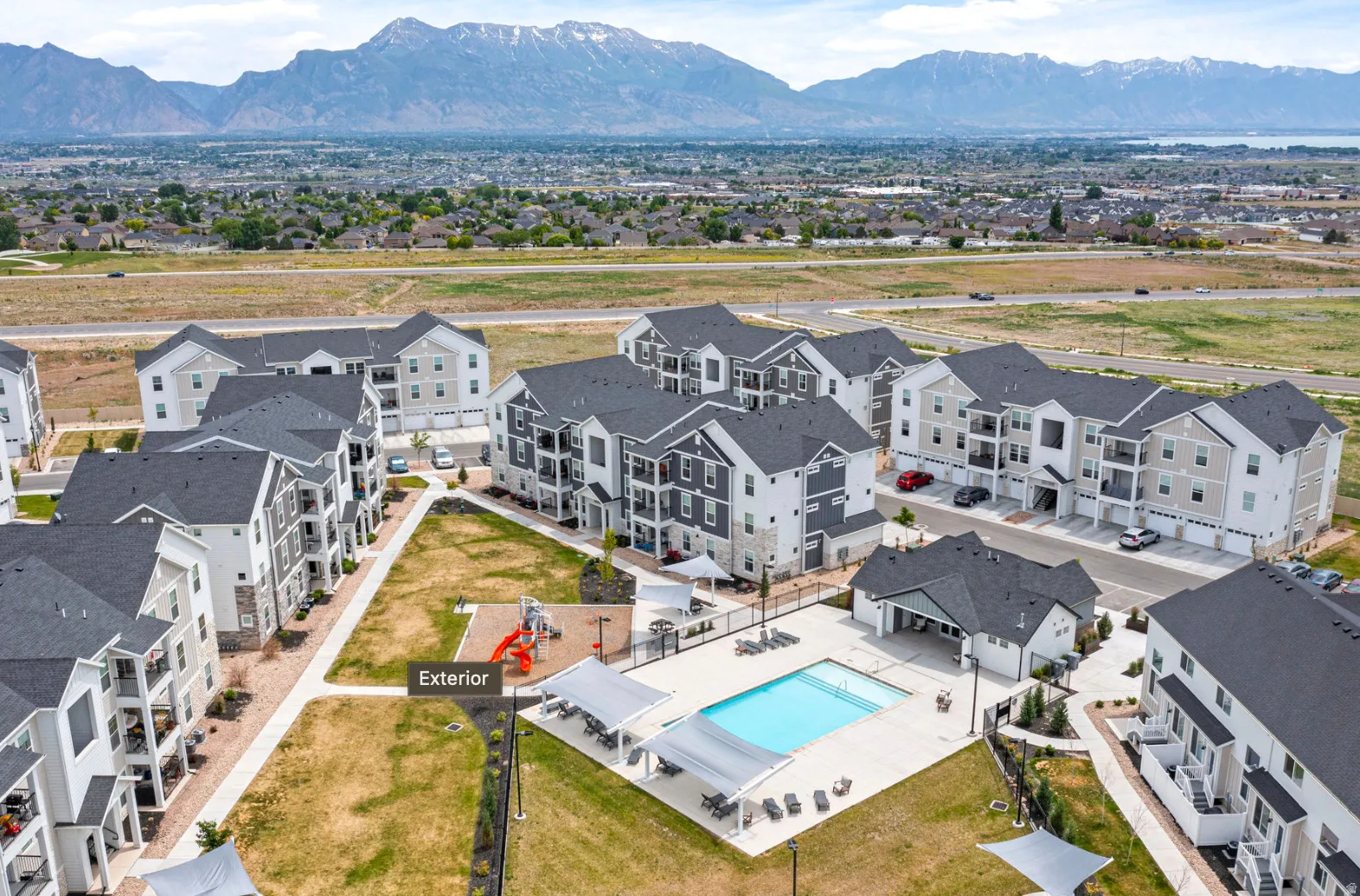 Multi-level residential buildings featuring dark gray shingle roofs and light-toned siding
