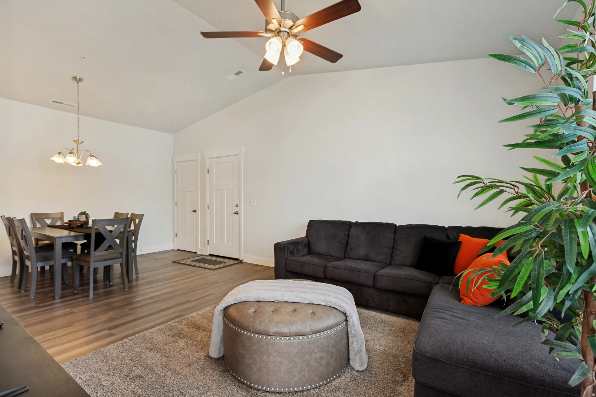 Vaulted ceiling with a ceiling fan, wood-finish flooring, and white interior doors