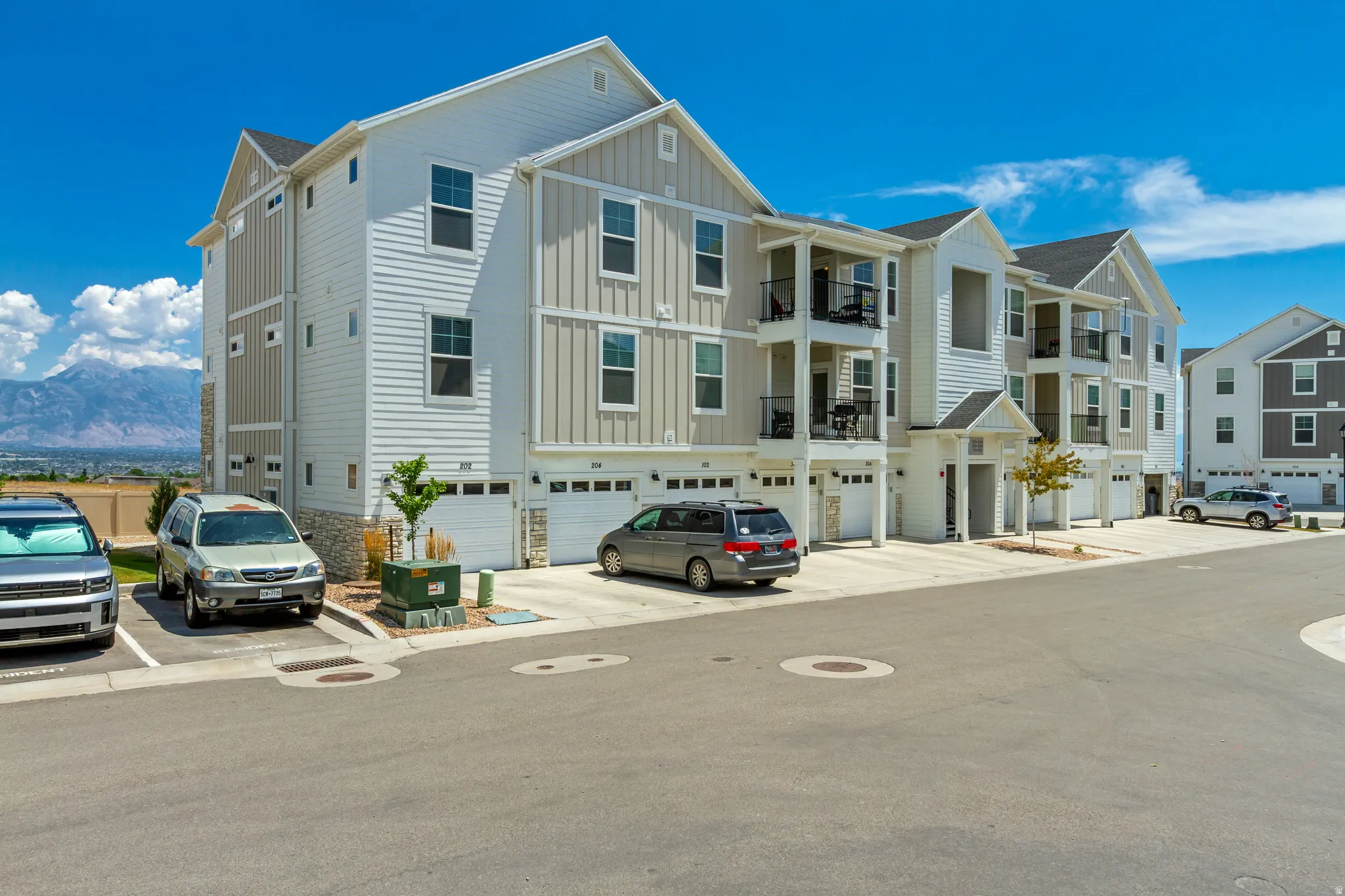Modern townhome exterior featuring white horizontal siding, light gray vertical siding, and stone accents