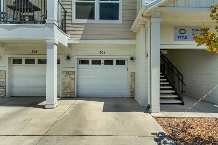 Facade featuring two single-car garages, an external staircase, and a second-story balcony