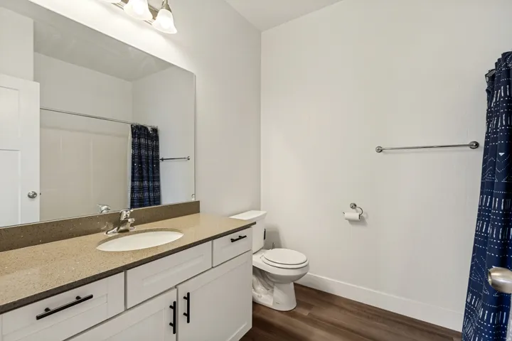 Bathroom vanity featuring a light-colored countertop, an undermount sink, and white cabinetry with black hardware