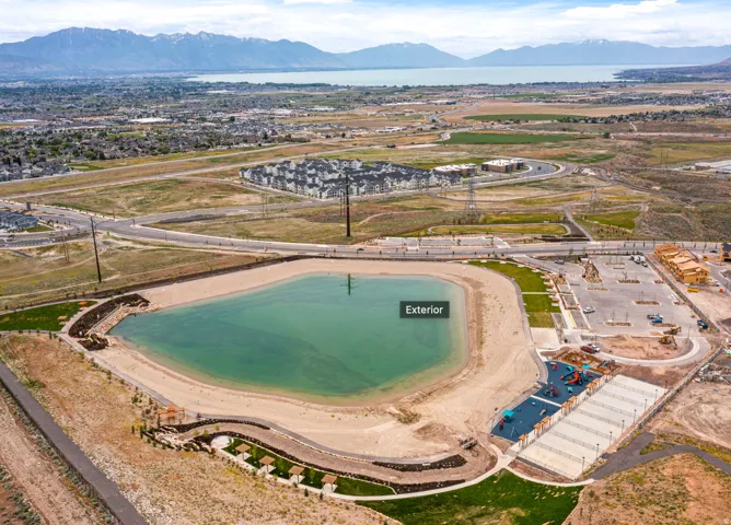 Aerial perspective of a developed recreational area featuring a large artificial lake, sandy shoreline, and integrated landscaping