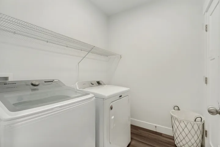 Dedicated laundry space featuring wood-finish flooring, white walls, and a convenient wire shelving unit