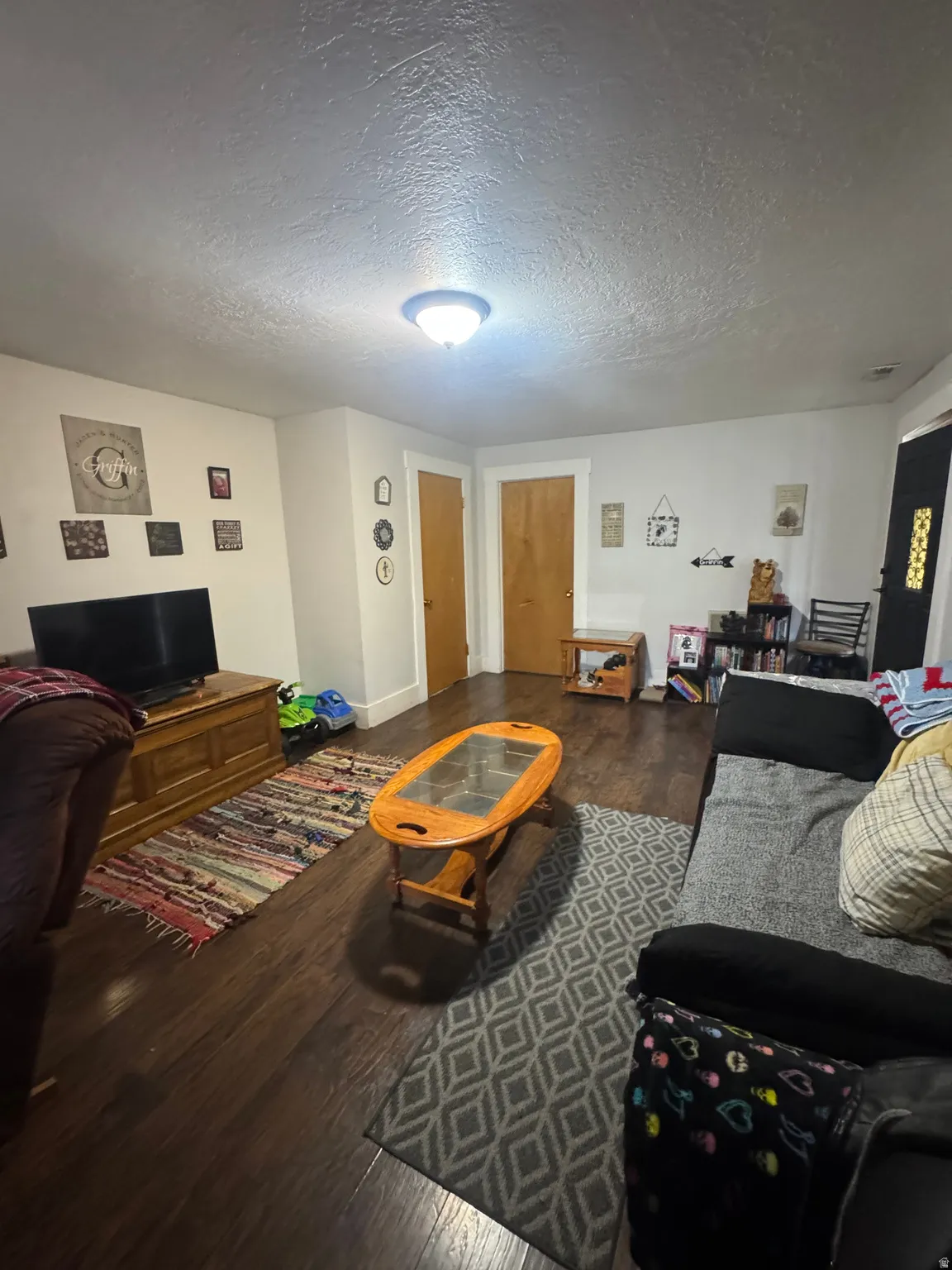 Spacious room featuring wood-finish flooring, light-toned walls, and multiple solid wood doors with white trim