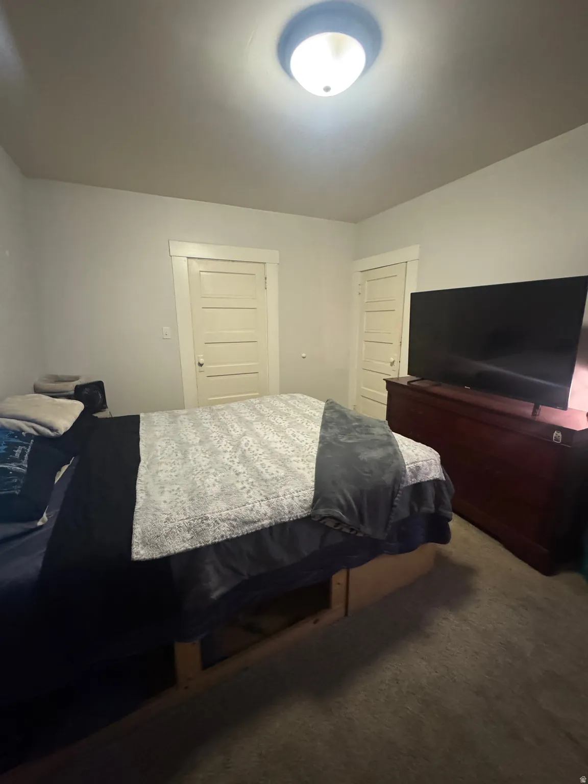 Bedroom featuring a flush-mount ceiling light fixture, two panel-style doors with casing, and neutral wall paint