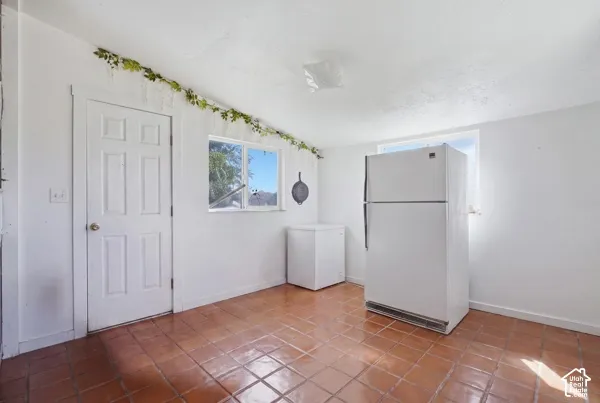 Mud Room/Office/Bedroom Terracotta tile flooring, white interior door, two windows providing natural light, and a white ceiling-mounted light fixture