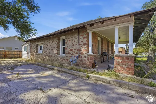 Stone exterior with white trim windows and a covered front porch featuring brick columns