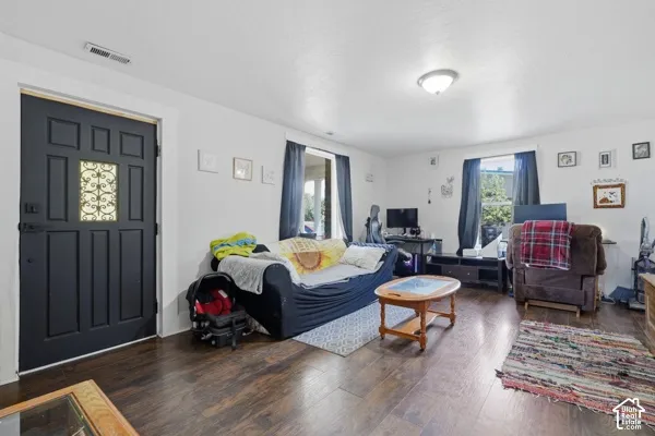Wood-finish flooring, white walls, and a black paneled door with decorative glass inlay
