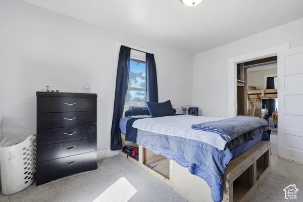 White painted walls, carpeted flooring, and a recessed window with dark drapery
