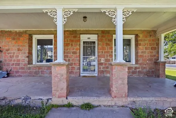 Stone exterior featuring a covered porch, decorative porch columns, and a security screen door
