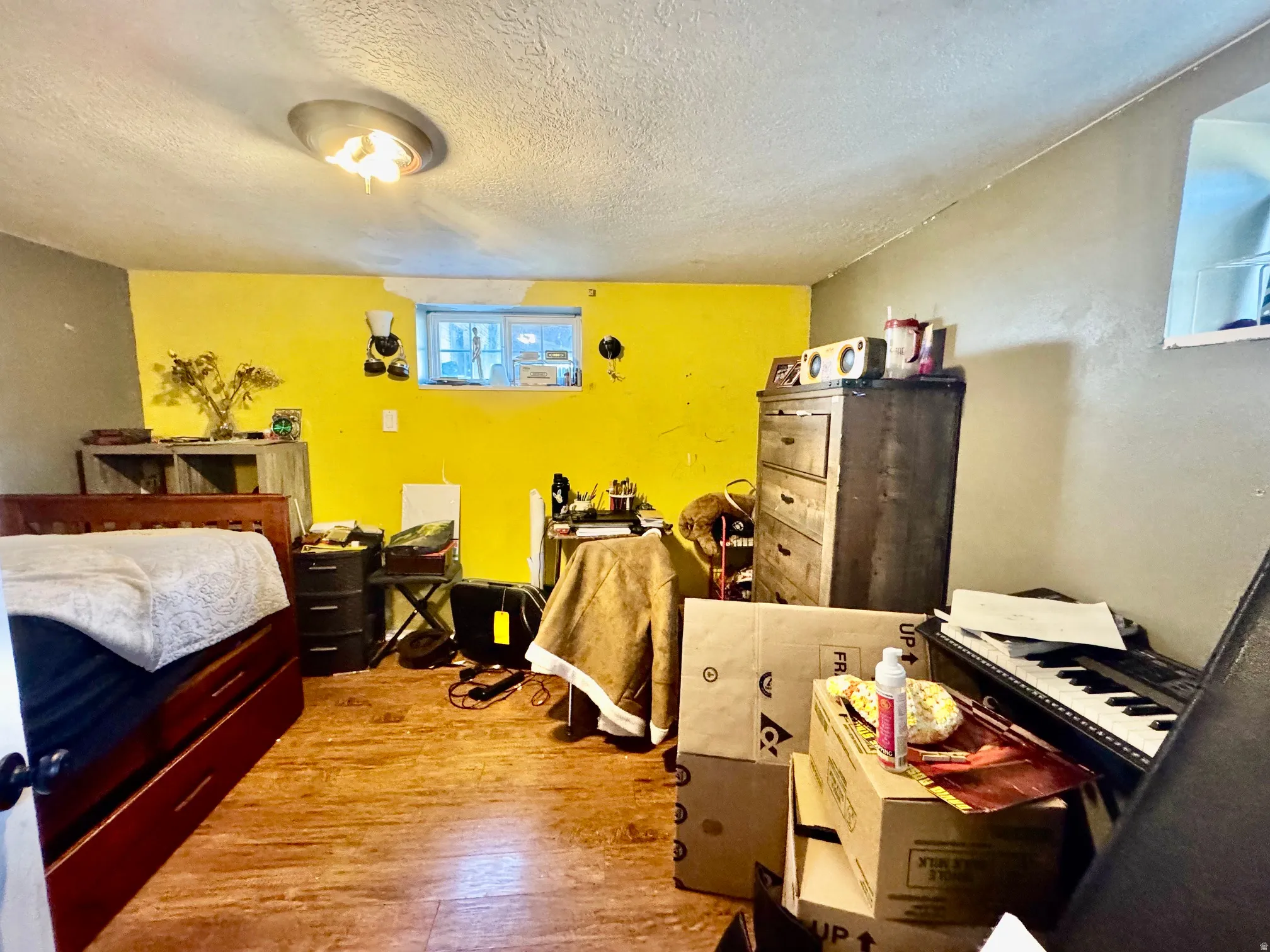 Room with wood-finish flooring, a combination of yellow and gray painted walls, and a ceiling-mounted light fixture