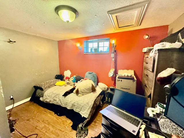 Room featuring wood-finish flooring, a wall-mounted light fixture, and a window providing natural light
