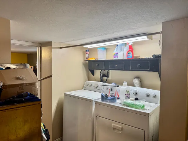 Dedicated laundry area featuring a washer and dryer, a built-in dark wood shelf with storage, and overhead strip lighting