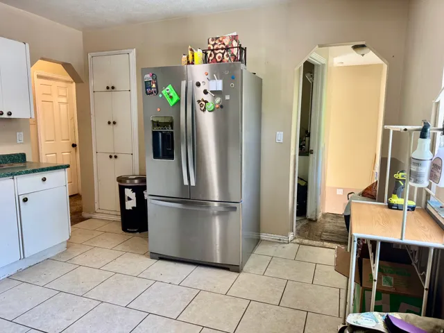 Kitchen area featuring white cabinetry, light-toned tile flooring, and a built-in pantry with multiple storage compartments