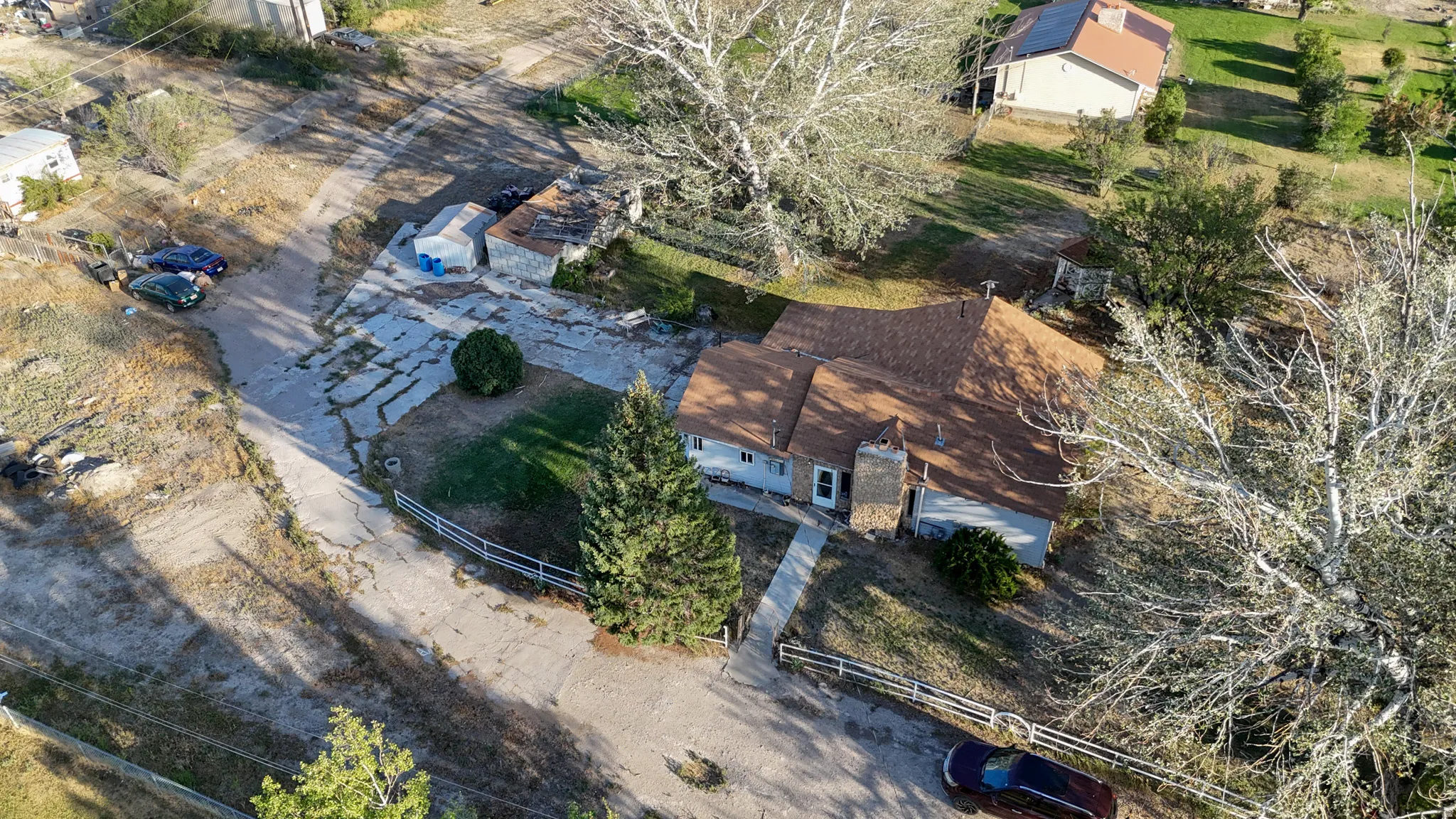 Single-story residence with a brown shingled roof, stone chimney, and light-colored siding