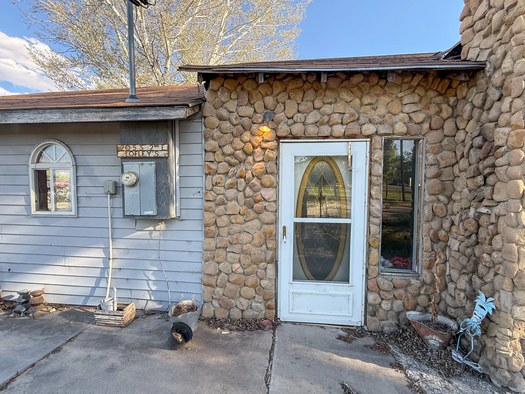 Stone facade entry with a decorative glass front door, complemented by a horizontal siding wing featuring an arched window