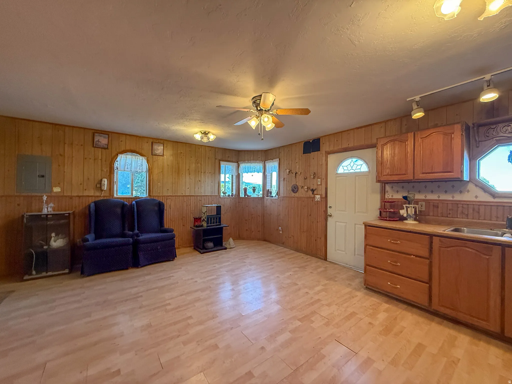 Open-concept area featuring wood-finish flooring, wood paneling, and an integrated kitchenette