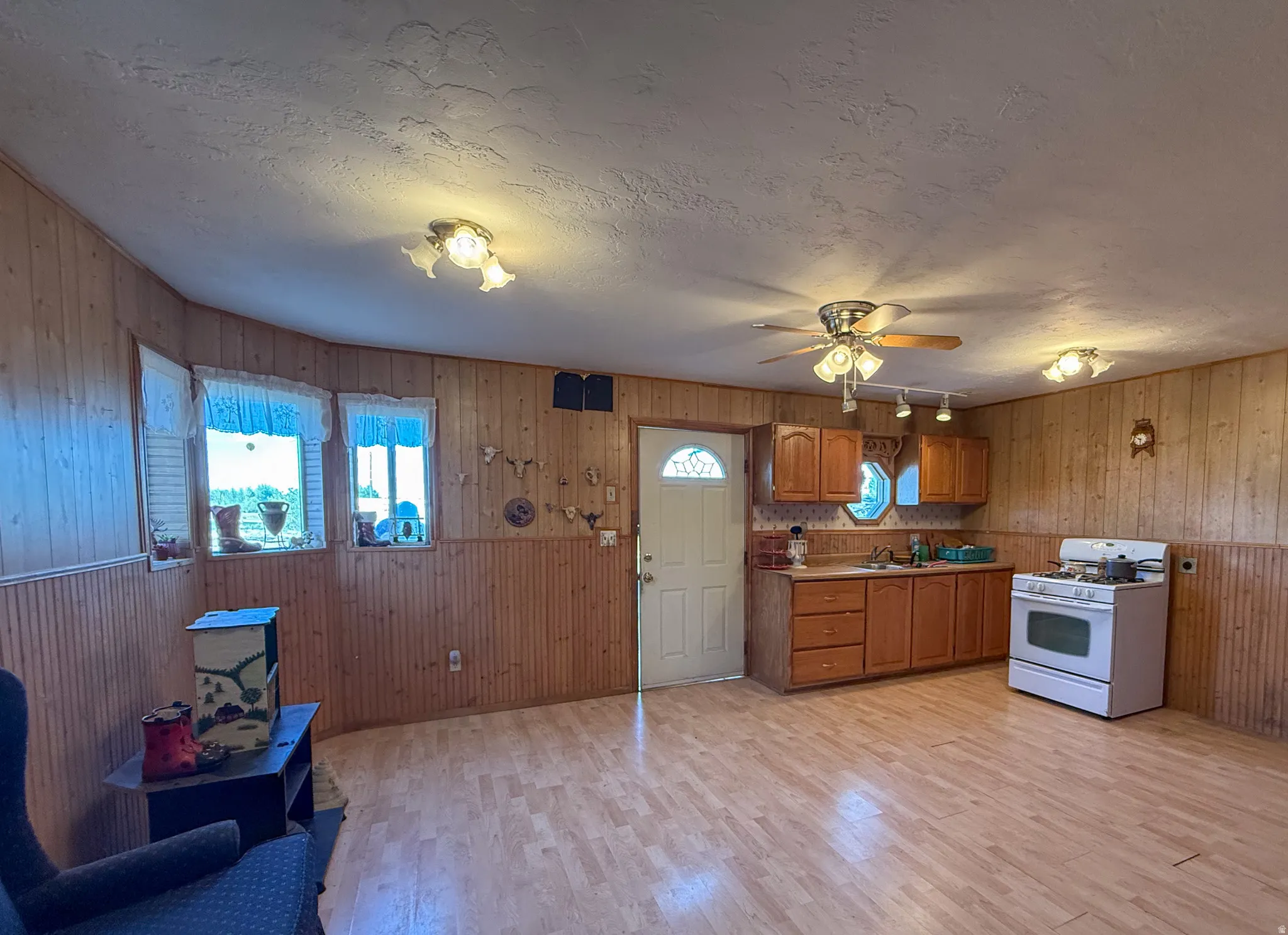 Open-concept living space featuring wood-finish flooring, wood paneling, and multiple windows