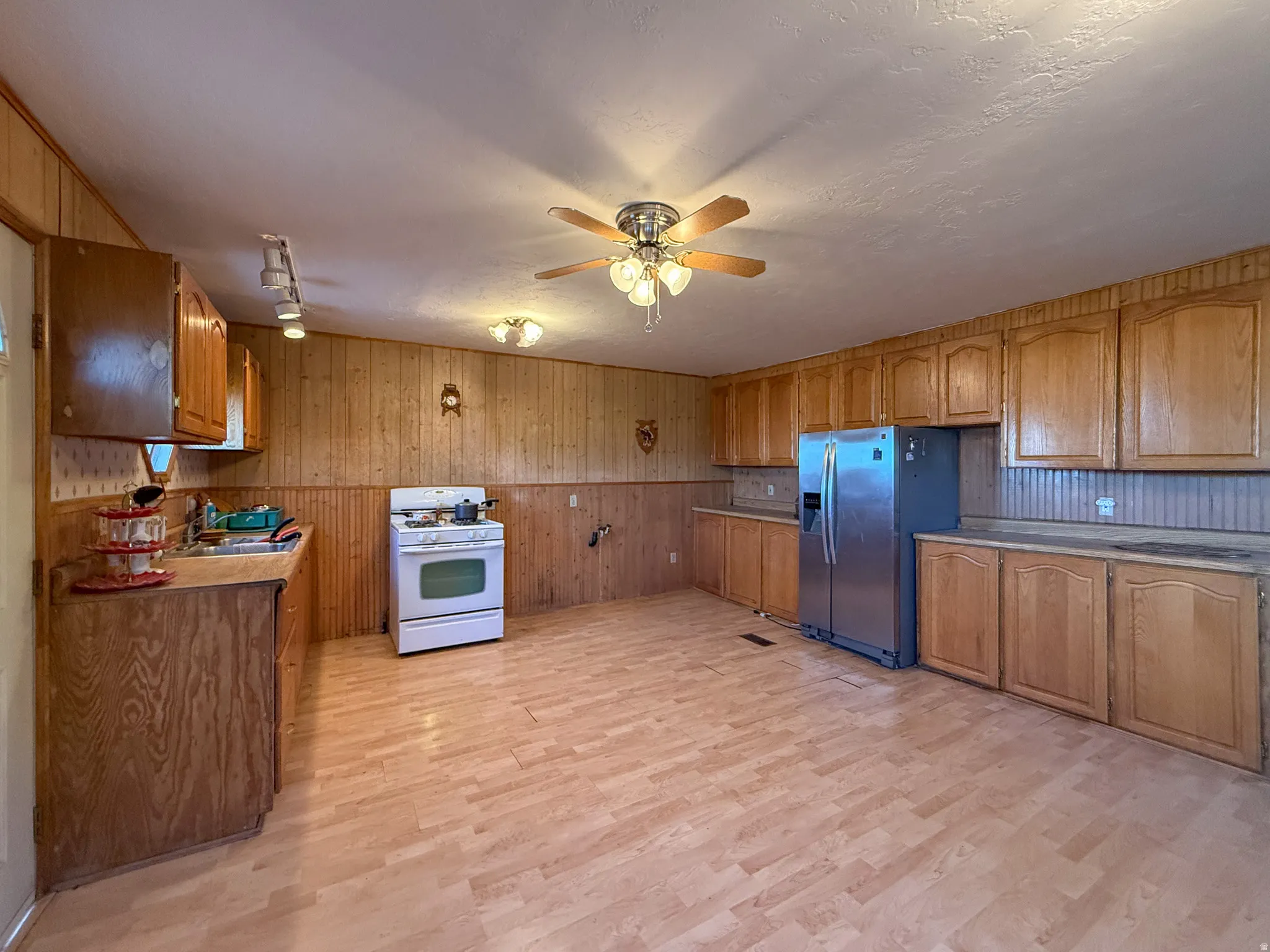 Spacious kitchen featuring extensive wood-finish cabinetry, light wood-finish flooring, and wood-paneled walls
