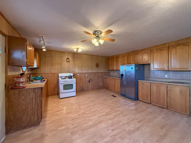 Spacious kitchen featuring extensive wood-finish cabinetry, light wood-finish flooring, and wood-paneled walls