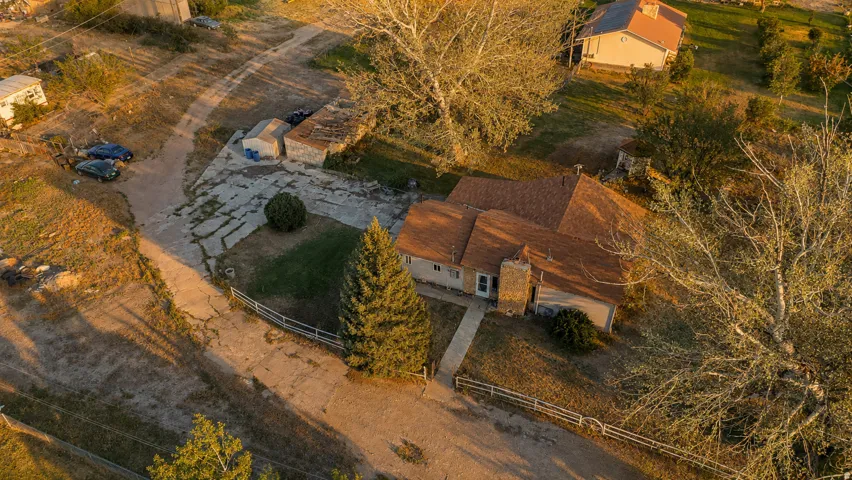 Single-story residence featuring a brown shingle roof, stone-clad chimney, and a concrete pathway