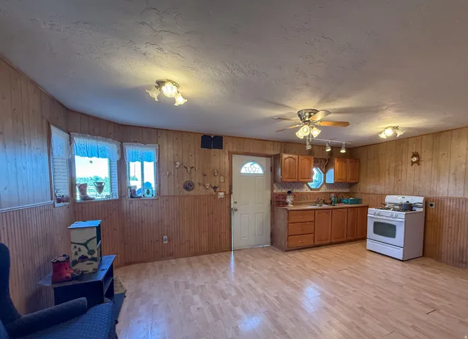 Open-concept living space featuring wood-finish flooring, wood paneling, and multiple windows
