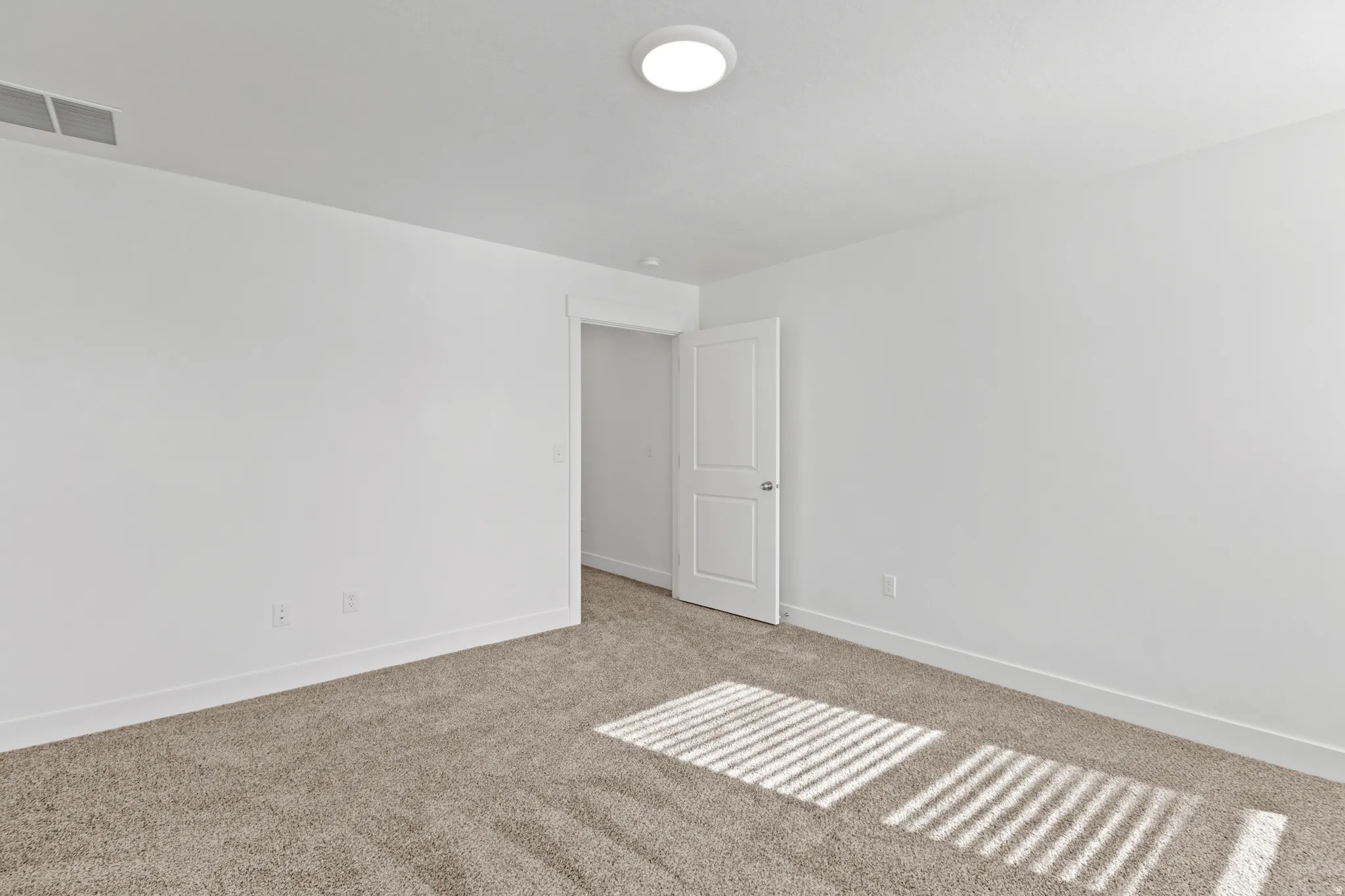 Spacious room with plush carpeting, crisp white walls, contemporary baseboards, and a recessed ceiling light fixture