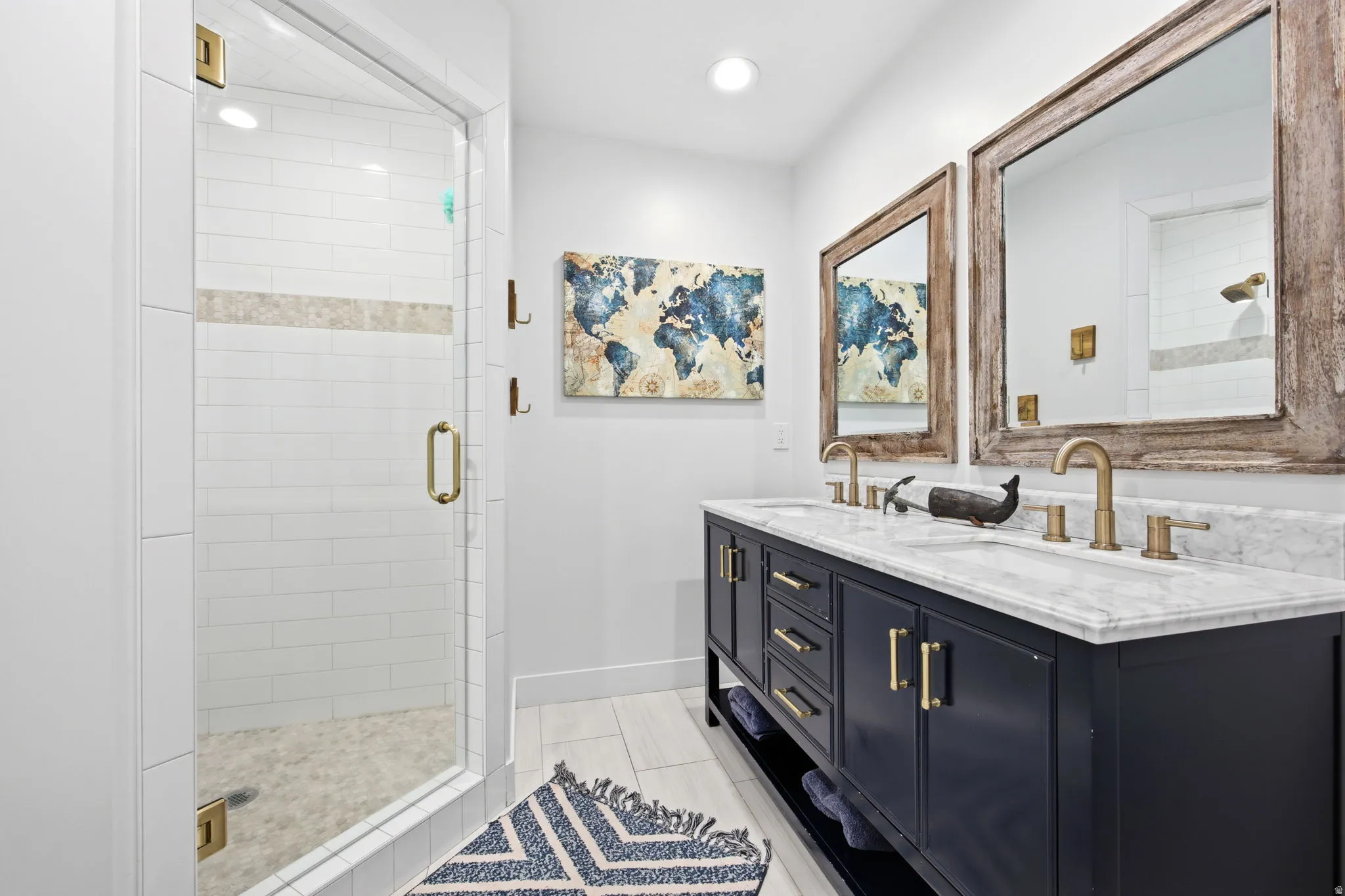 Dual vanity featuring a marble countertop, undermount sinks, and gold-finish fixtures