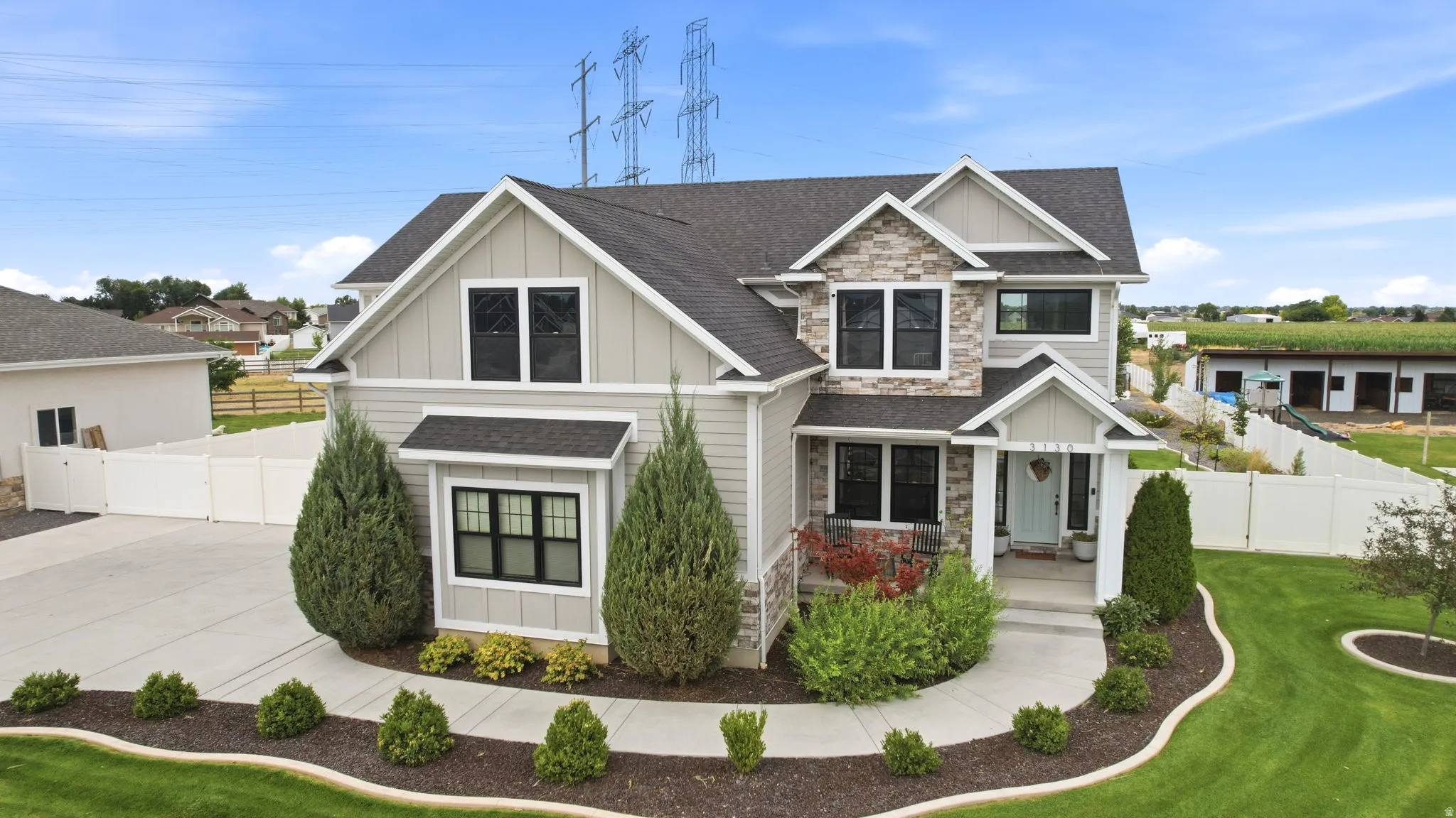 Contemporary dwelling featuring stone and siding exterior, dark framed windows, a covered front porch, and a concrete driveway