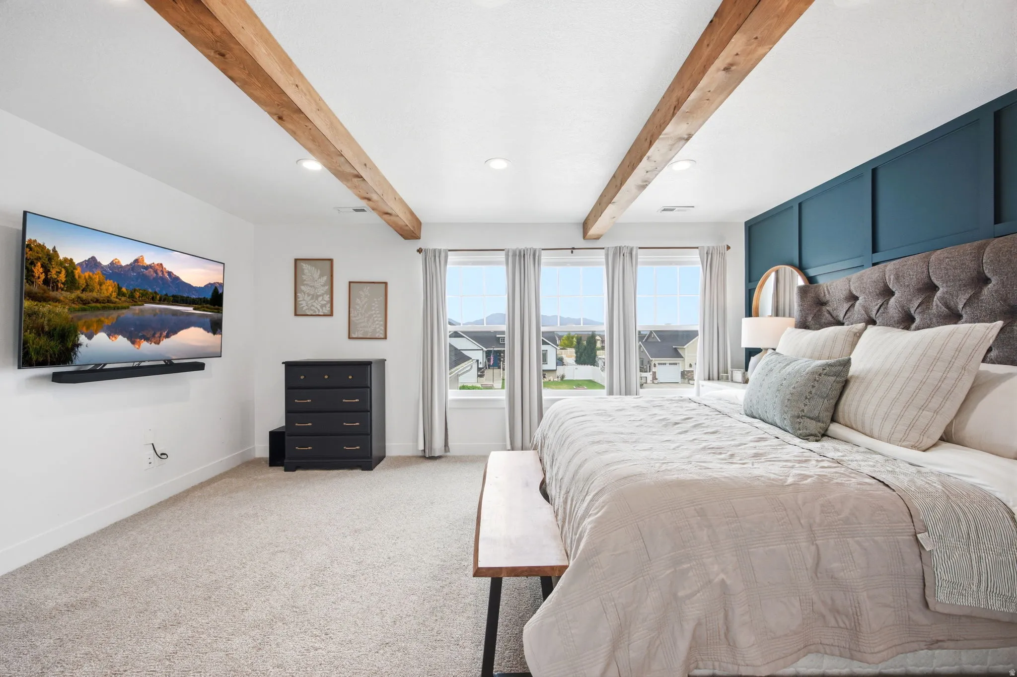 Spacious room featuring exposed wood ceiling beams, three large windows, recessed lighting, and soft carpet flooring