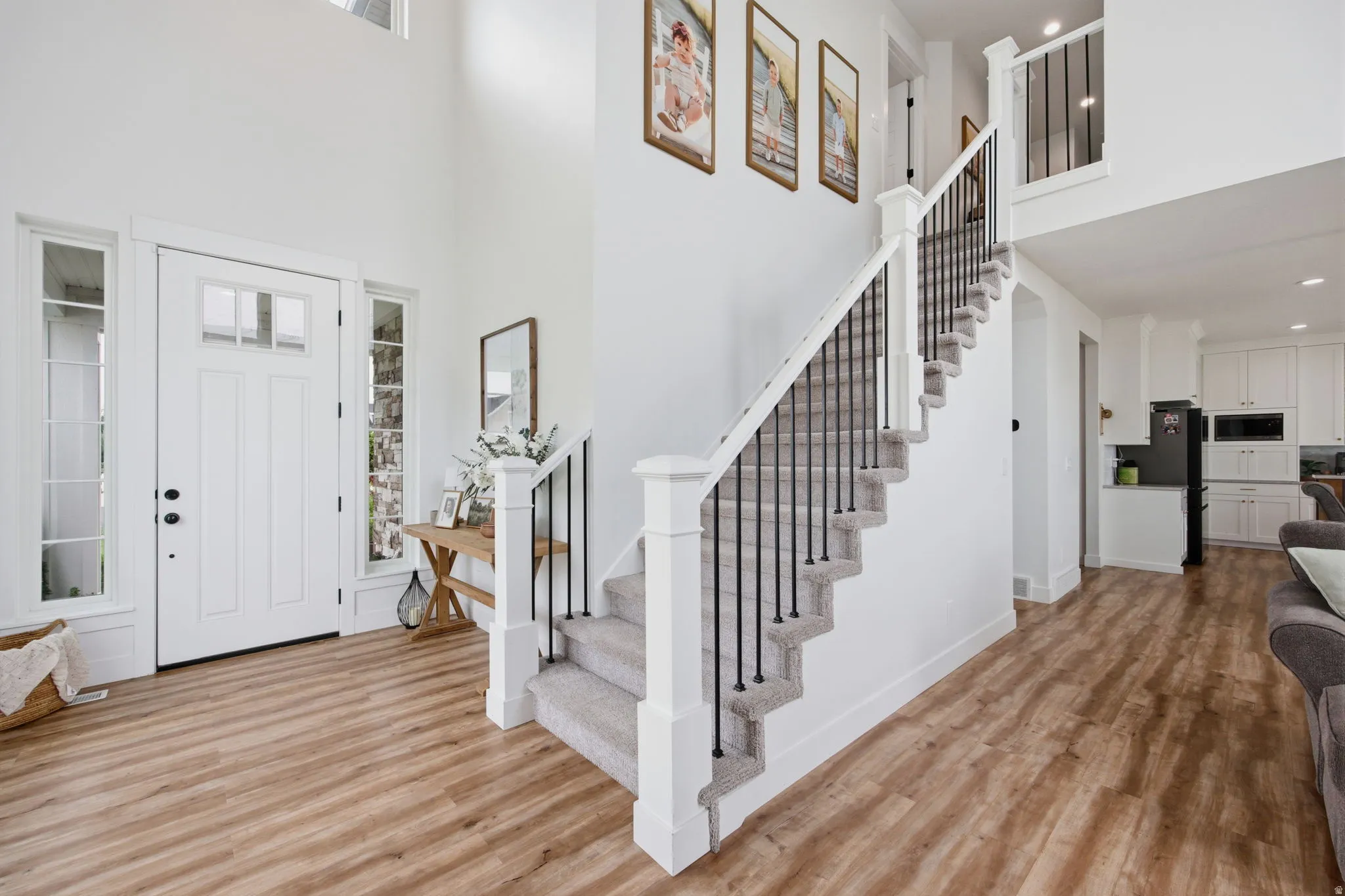 Two-story foyer featuring a staircase with black iron spindles, light wood-finish flooring, and a white front door with sidelights