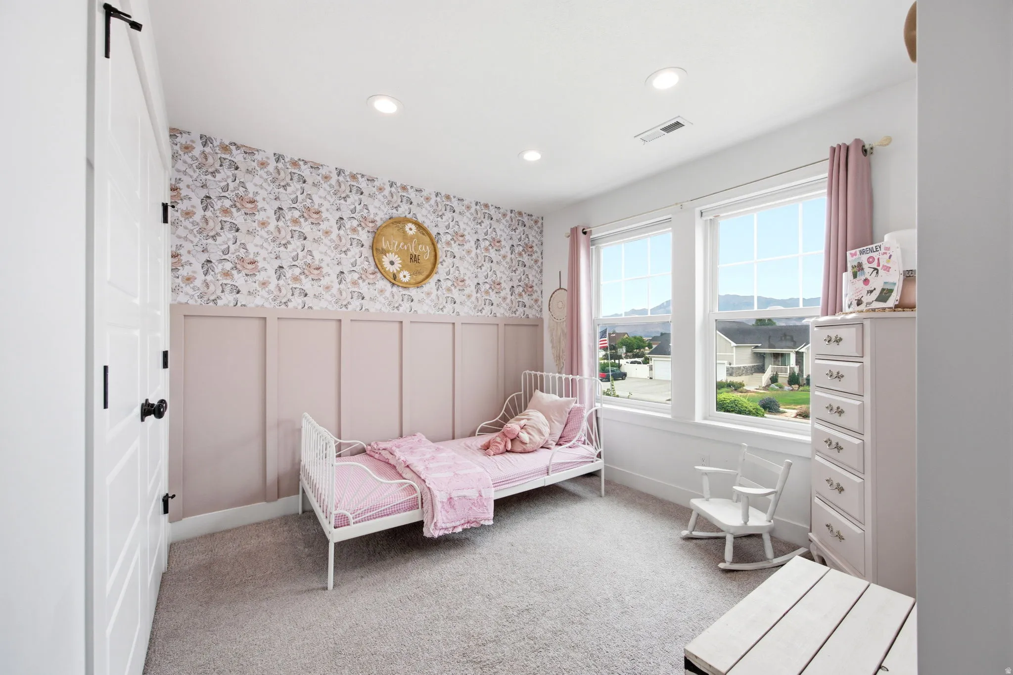 Bedroom featuring a decorative accent wall with wainscoting and floral wallpaper