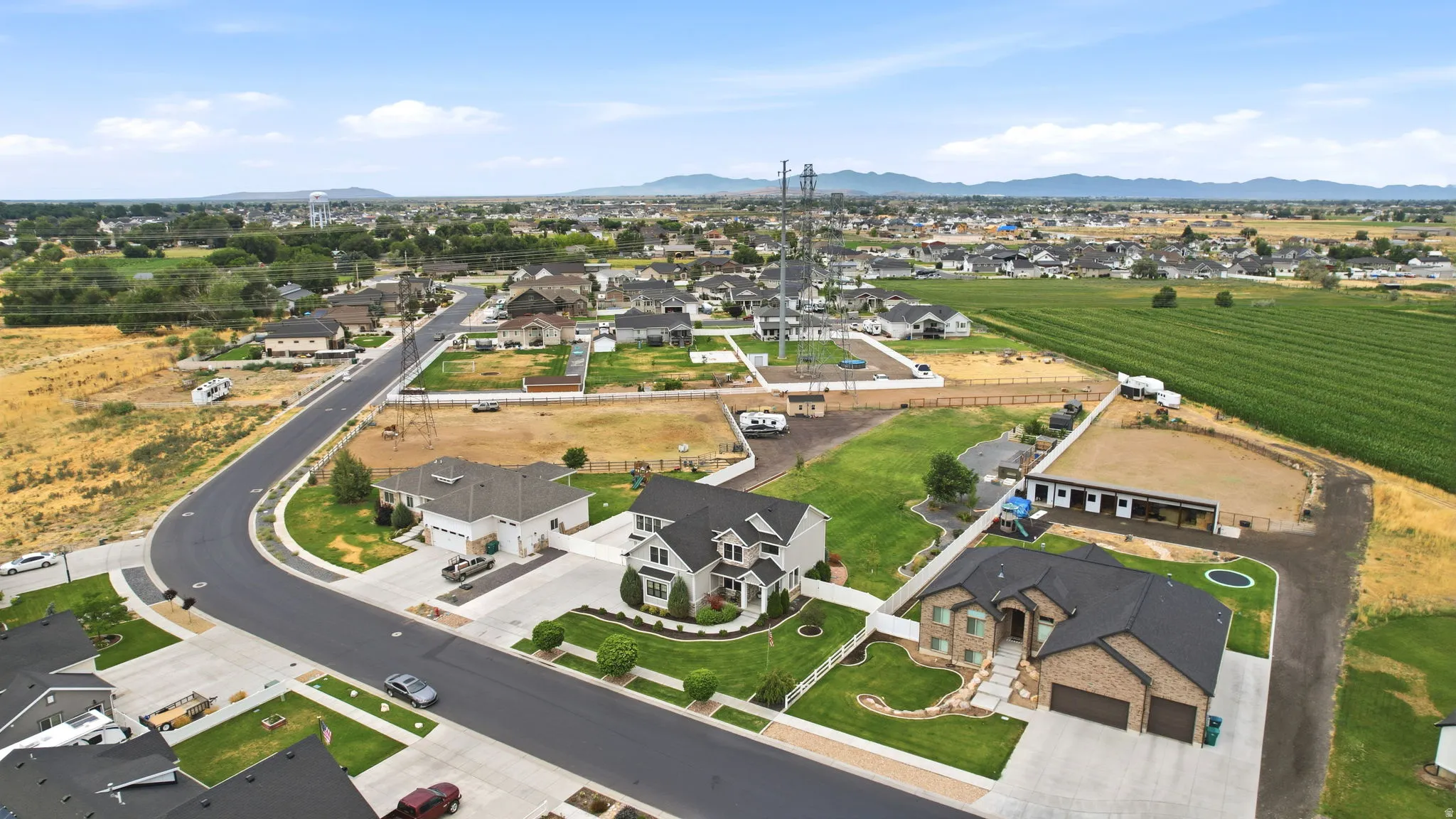 Aerial overview of a residential neighborhood with surrounding agricultural land and distant mountains