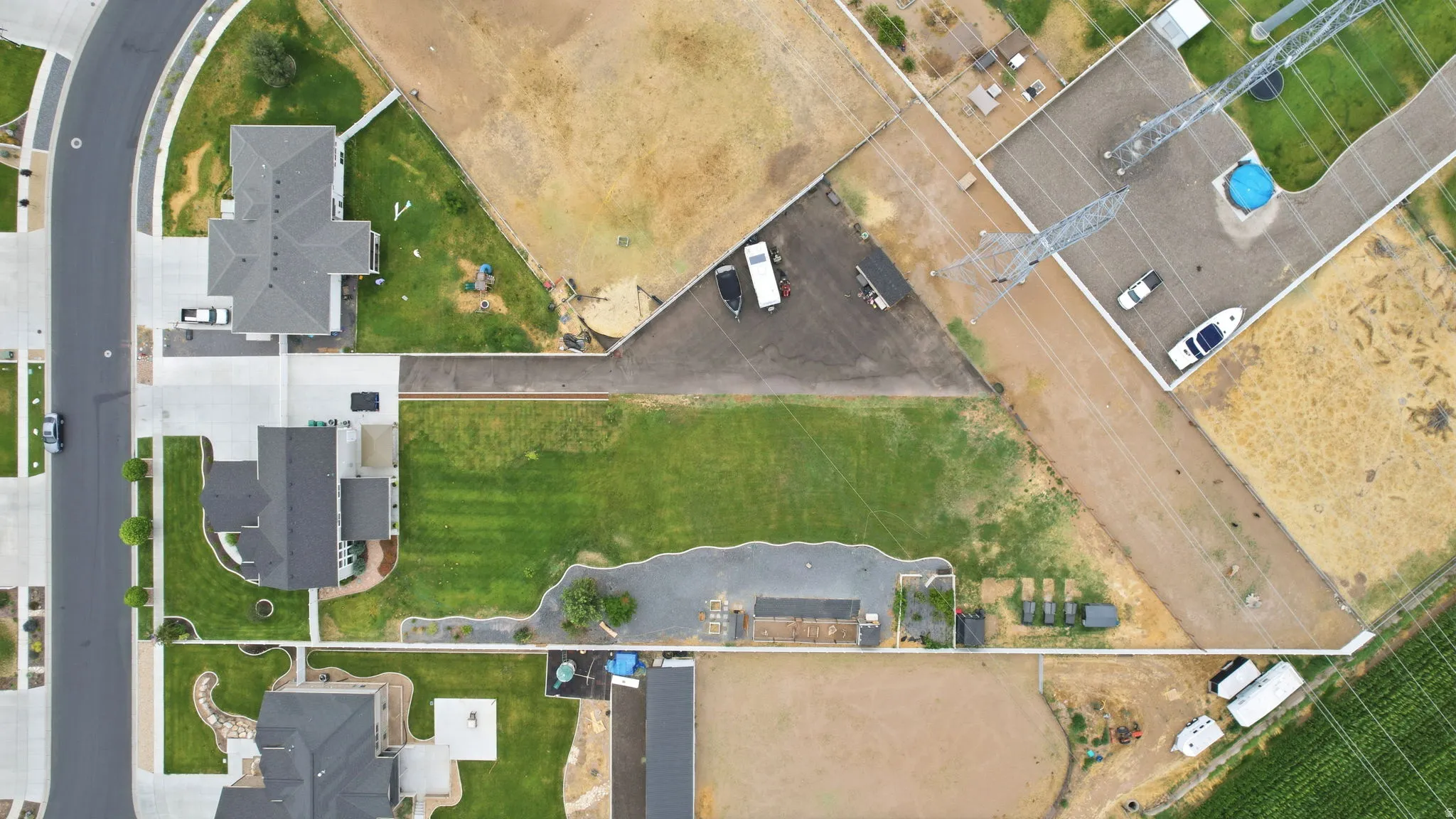 Expansive property featuring a substantial green lawn, concrete driveways, and a paved street