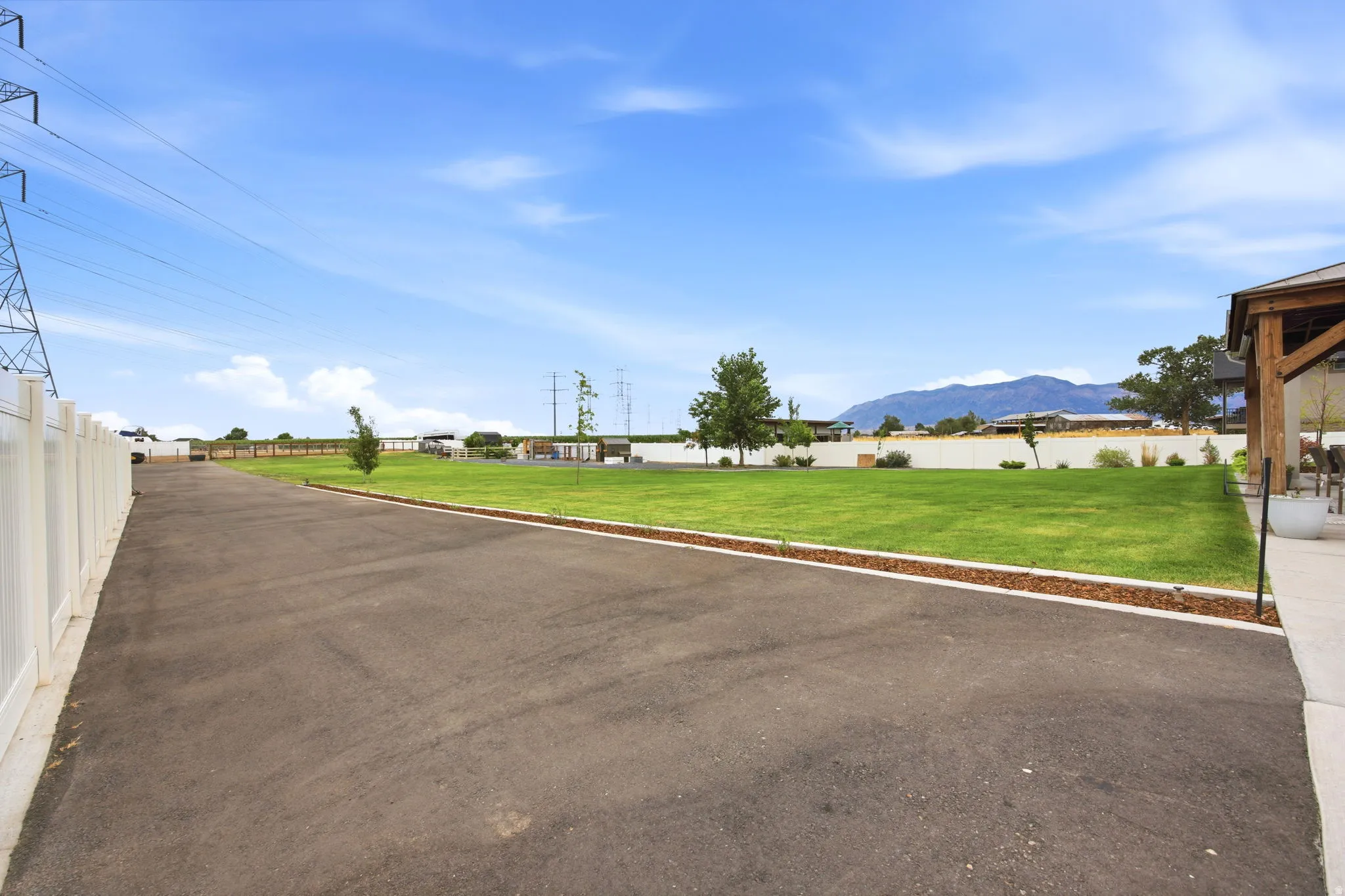 Expansive paved driveway bordered by a white privacy fence and a manicured lawn