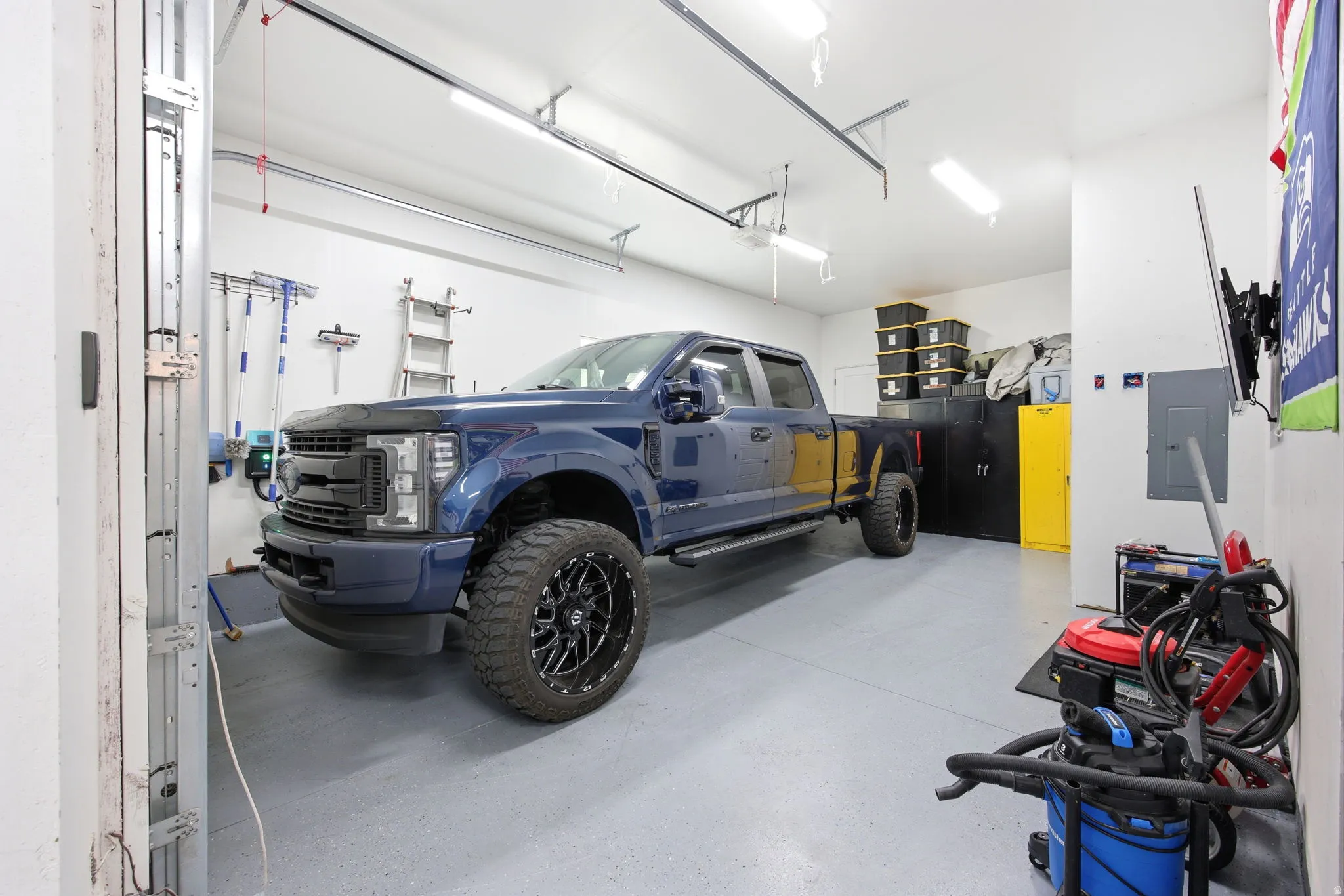 Spacious garage featuring a durable epoxy-coated floor, bright overhead fluorescent lighting, and overhead garage door tracks