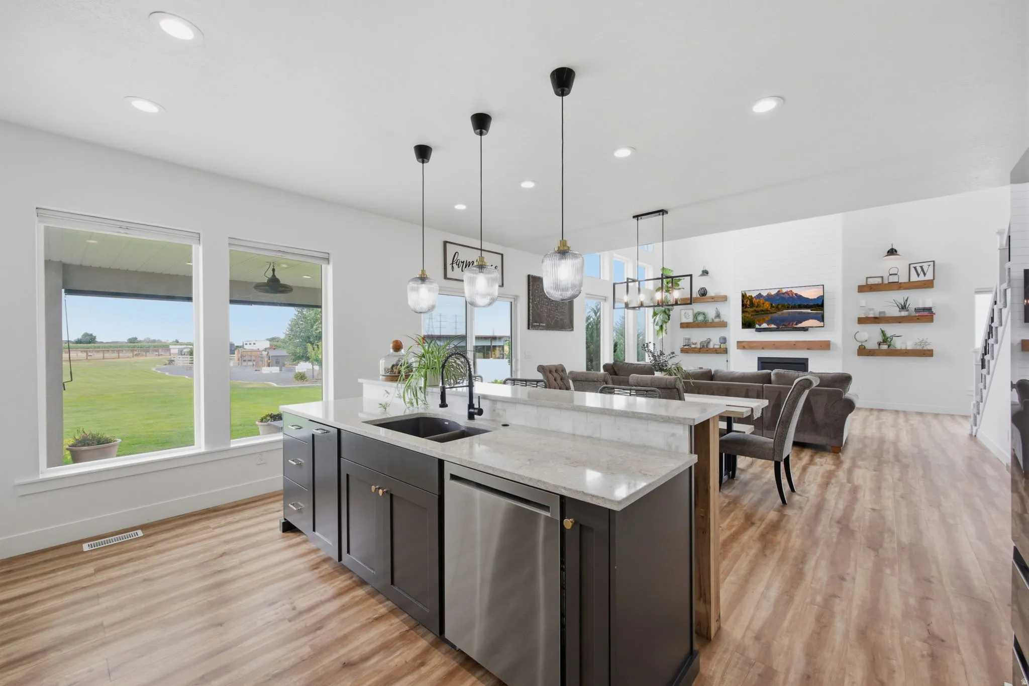 Kitchen island featuring dark cabinetry, a double basin sink with a matte black faucet, and a stainless steel dishwasher